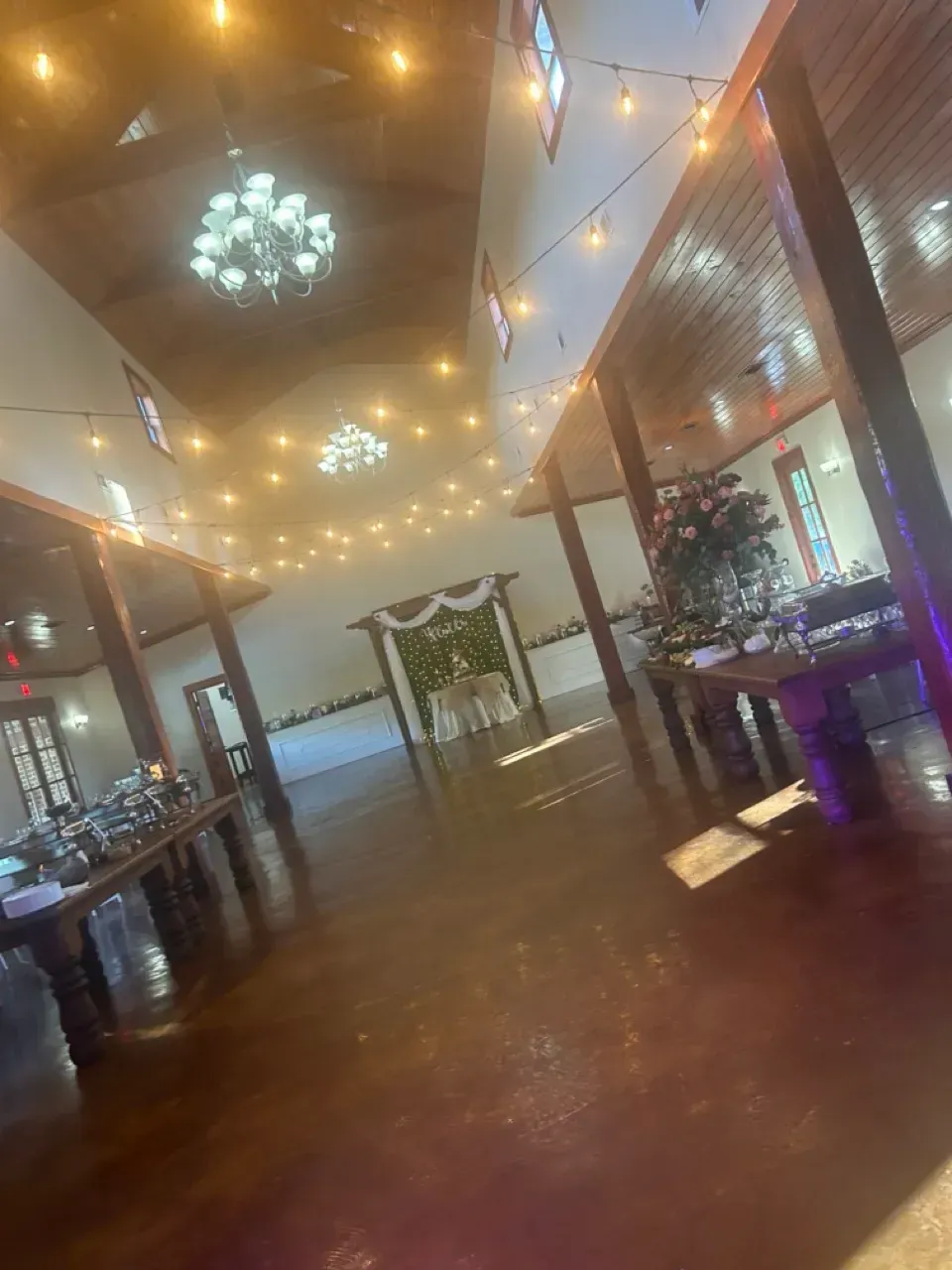 Empty restaurant interior with warm string lights, chandeliers, and tiled flooring