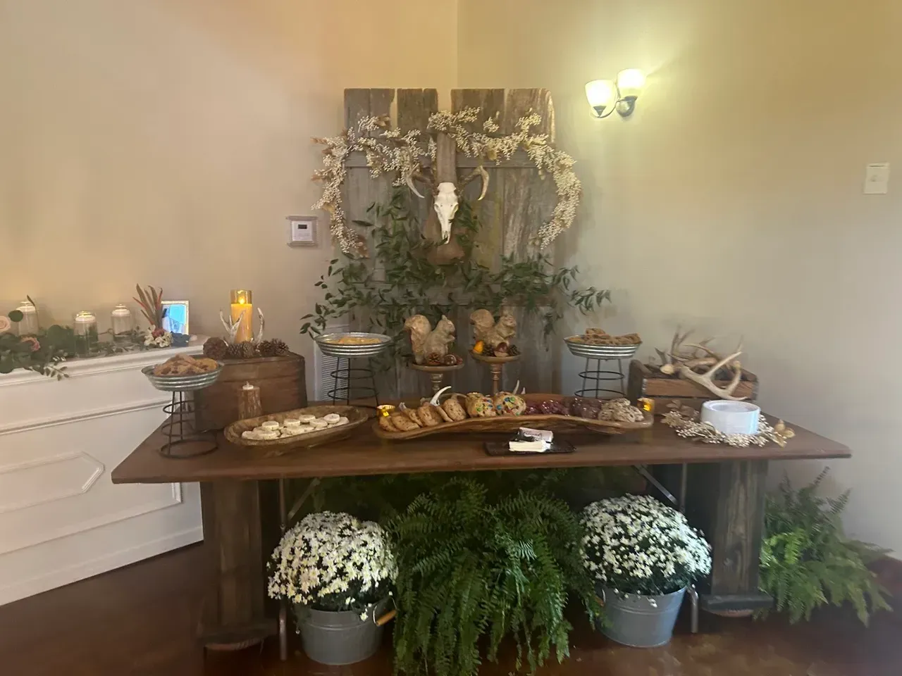 Decorated buffet table with greenery, candles, and flowers in a softly lit room