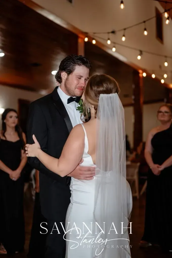 Bride and groom slow dancing at a wedding reception under string lights