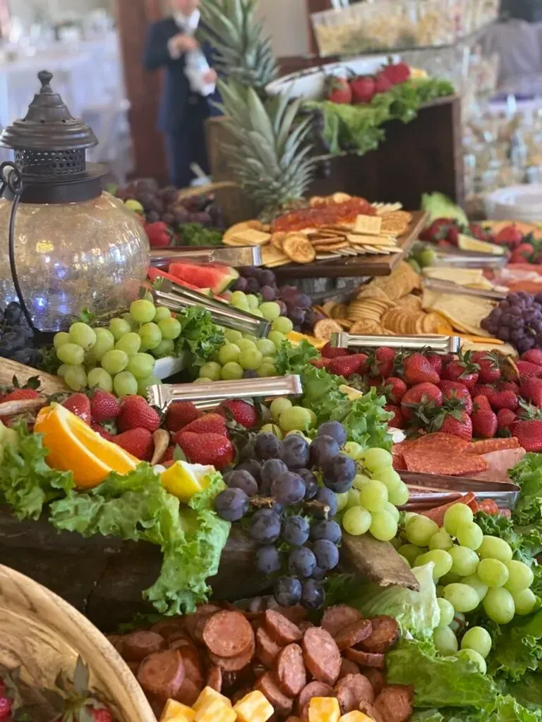 Gourmet buffet table with grapes, berries, cheese, crackers, and a decorative lantern