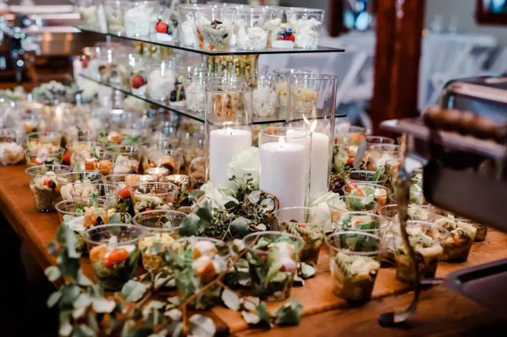 Buffet table with salads, candles, and greenery set for an elegant event