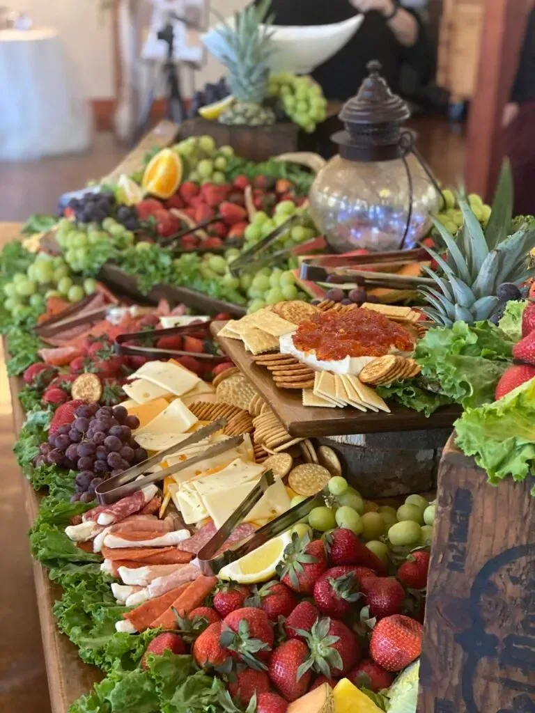 Fruit and cheese charcuterie display with grapes, strawberries, pineapple, and crackers on a buffet table