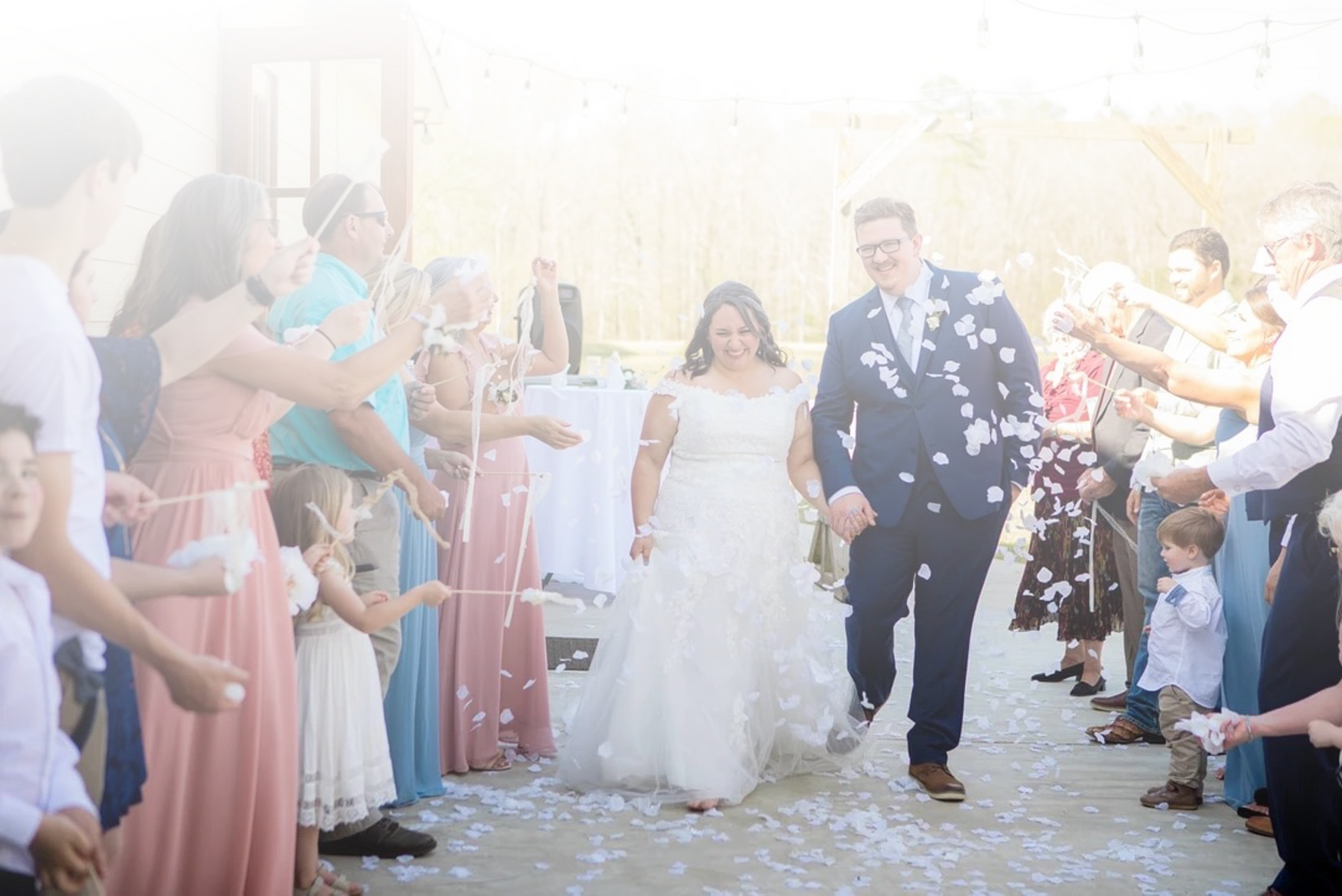 Wedding couple walking down an aisle under a shower of confetti, surrounded by cheering guests