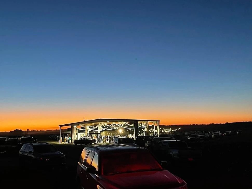 Dusk over a lit gas station with parked cars under a blue-orange sky