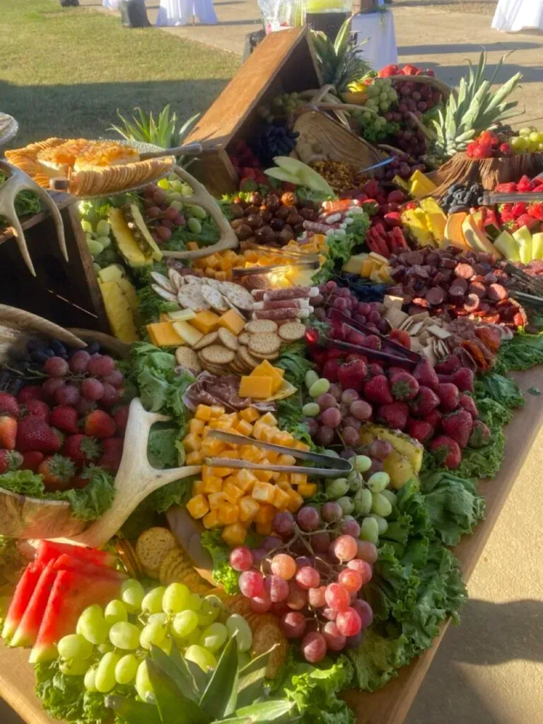 Colorful fruit display on a table, arranged in pyramids with grapes, berries, citrus, and melons.