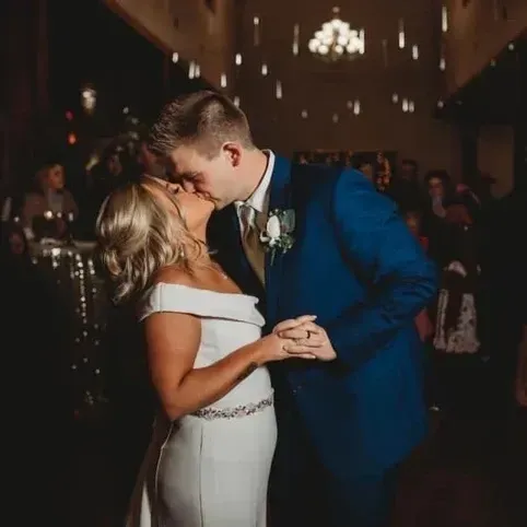 Bride and groom dancing and kissing in a dimly lit wedding venue