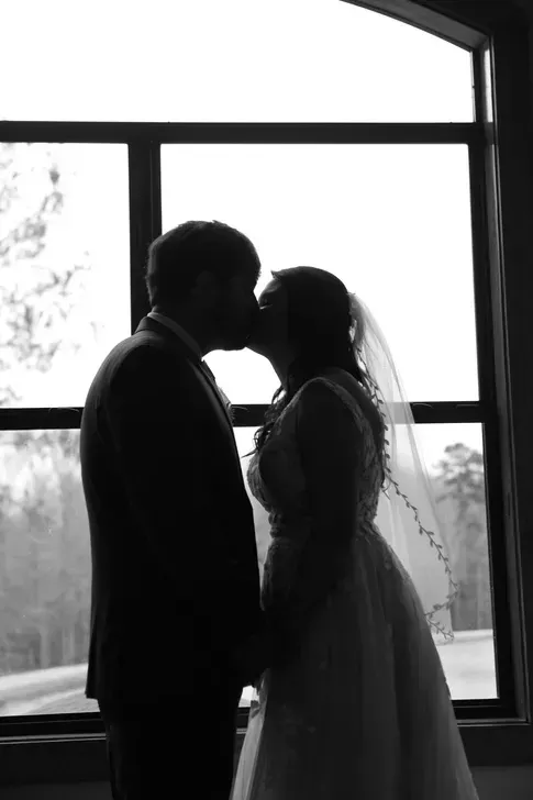 Silhouetted couple kissing in front of a large window in a bright room
