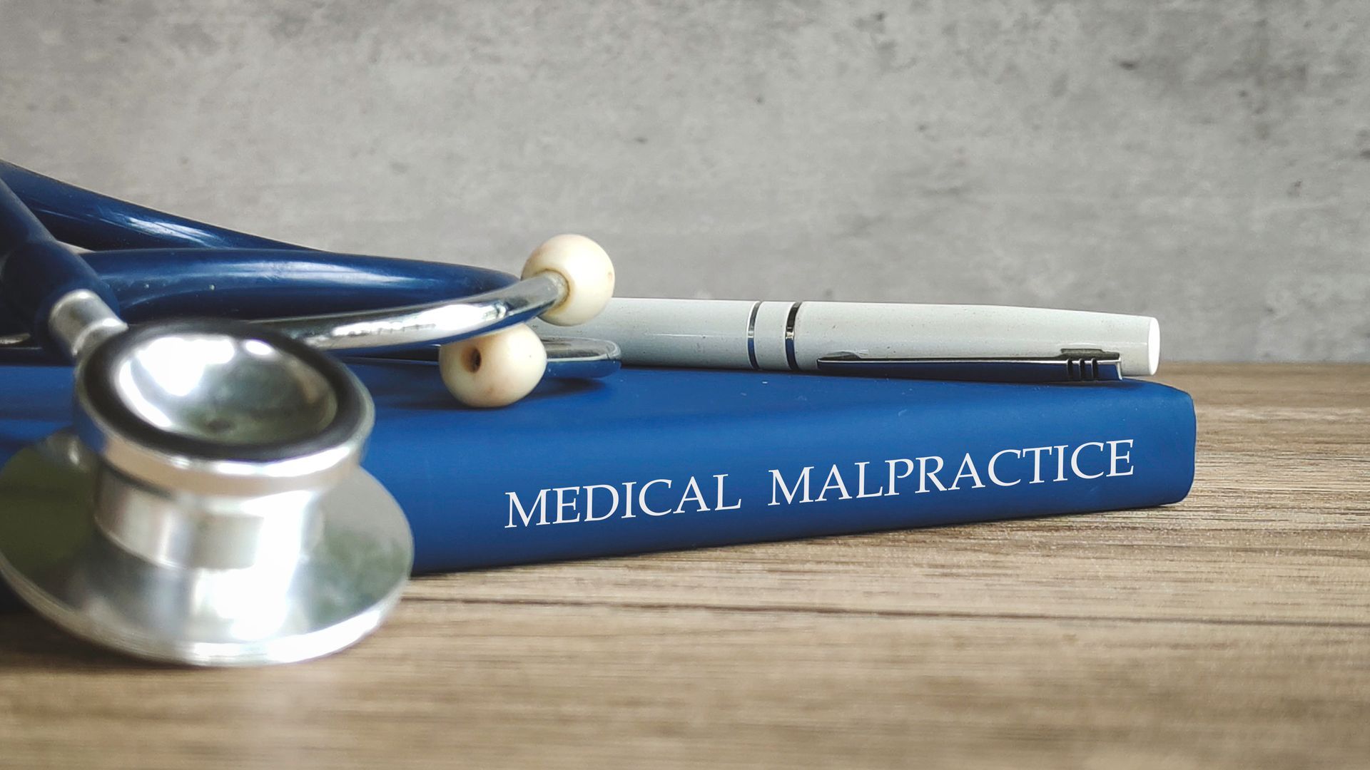 A stethoscope is on top of a book with the words “Medical Malpractice” on its spine. A stethoscope is on top of a book with the words “Medical Malpractice” on its spine.