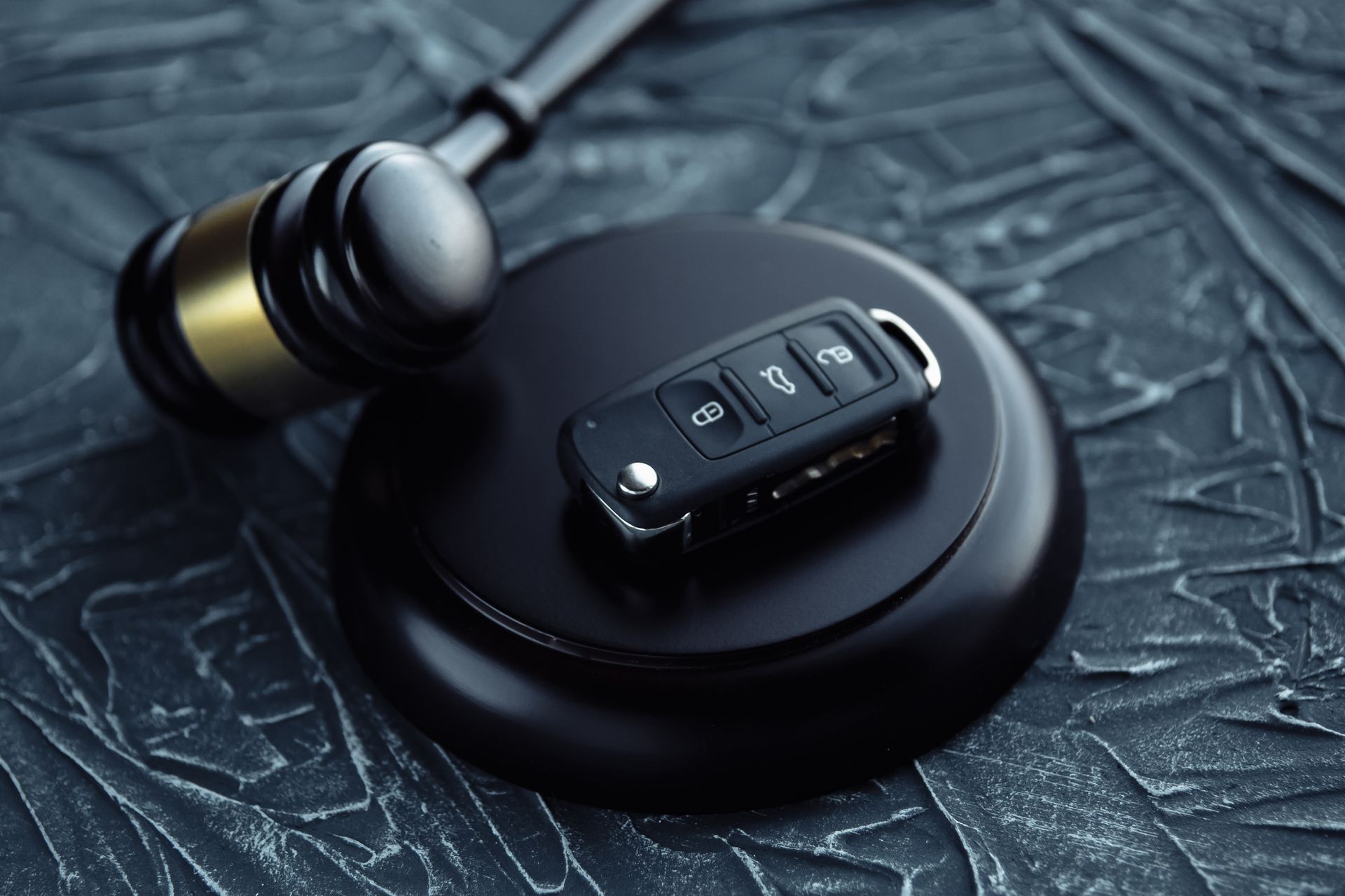 Gavel and car key on the wooden desk. 