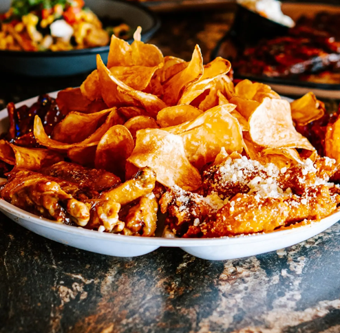 Plate of fried food: potato chips, chicken wings, and cheese.