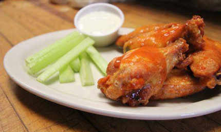 Plate of buffalo wings, celery sticks, and ranch dressing.