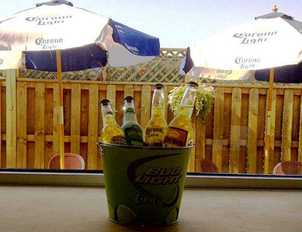 Bucket of beer bottles on a bar, with outdoor patio in the background.