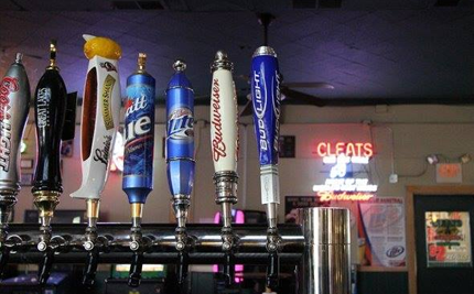 Beer taps in a bar, various brand names on tap handles, neon 