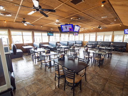Restaurant interior with tables, chairs, booths, TVs, and ceiling fans.