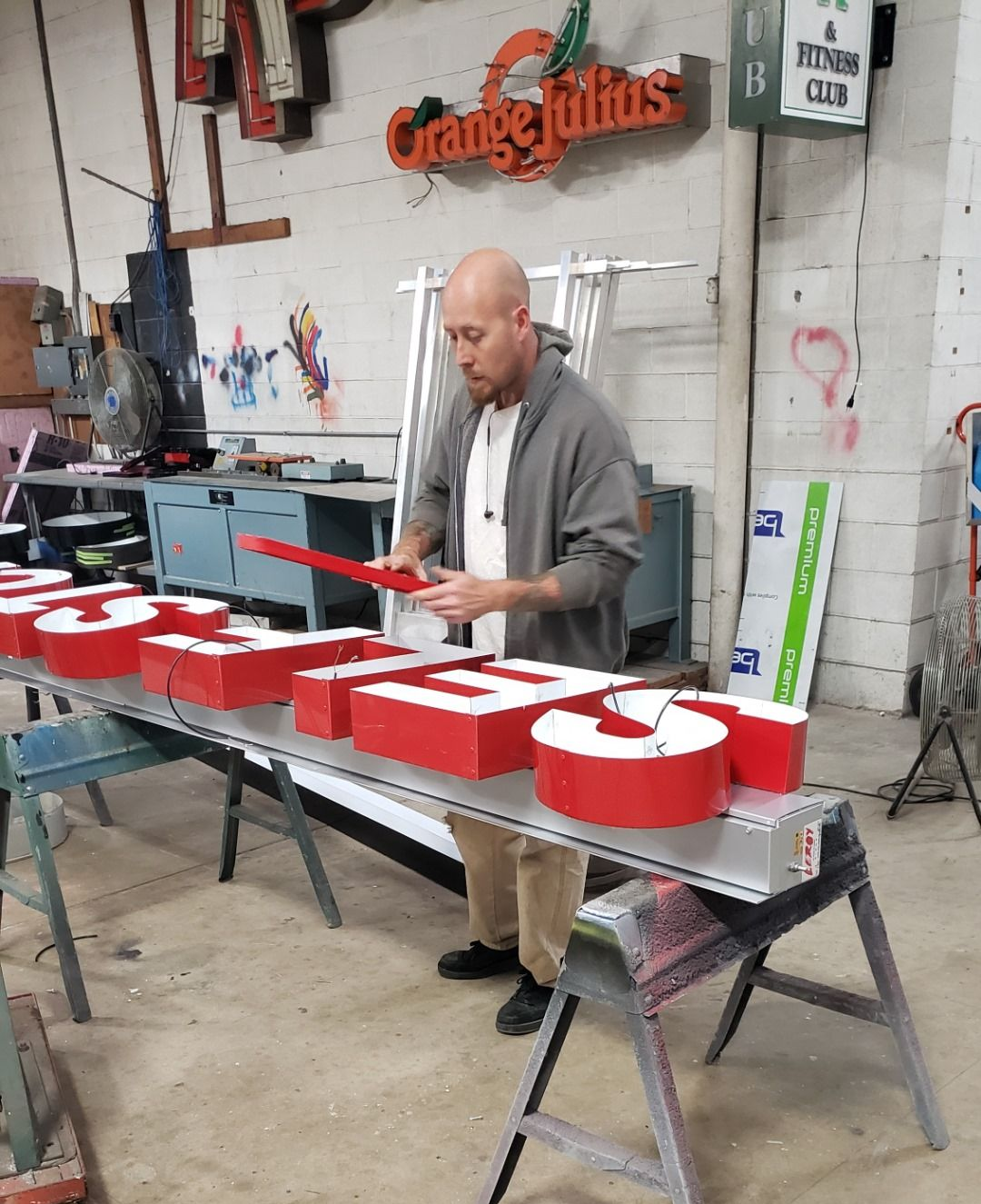 Man in workshop assembling red, lit sign letters. Man in workshop assembling red, lit sign letters.