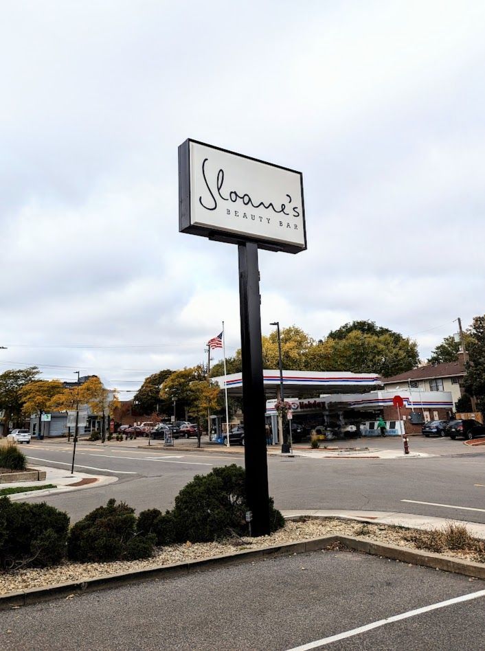 Street view of Sloane’s sign and storefront near a parking lot under a cloudy sky