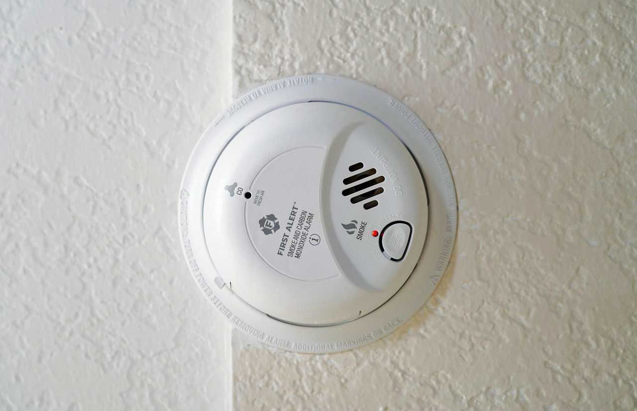 CO detector mounted on a textured, off-white ceiling.