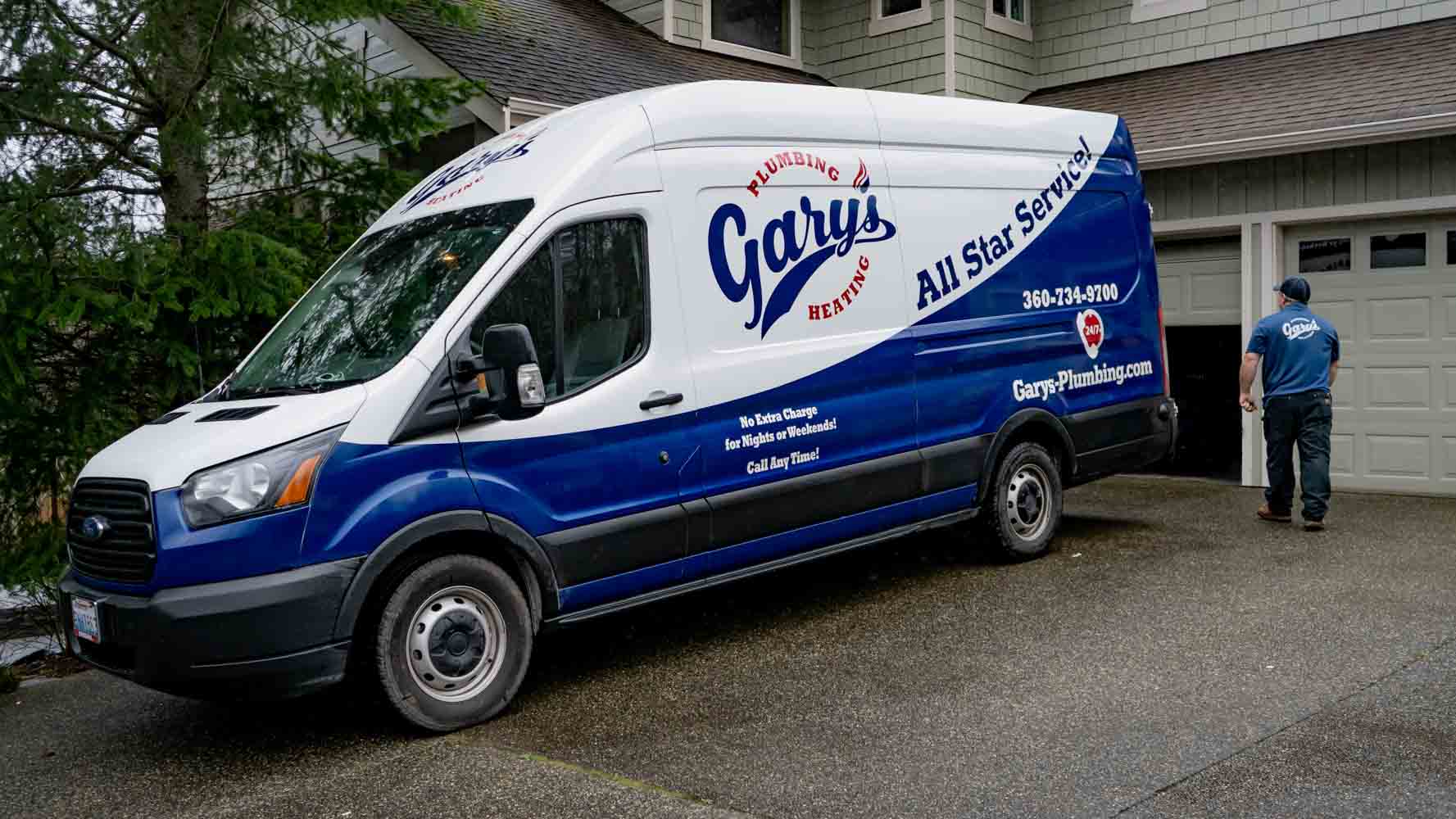 Blue and white delivery van parked on a gravel driveway, with a person standing nearby.