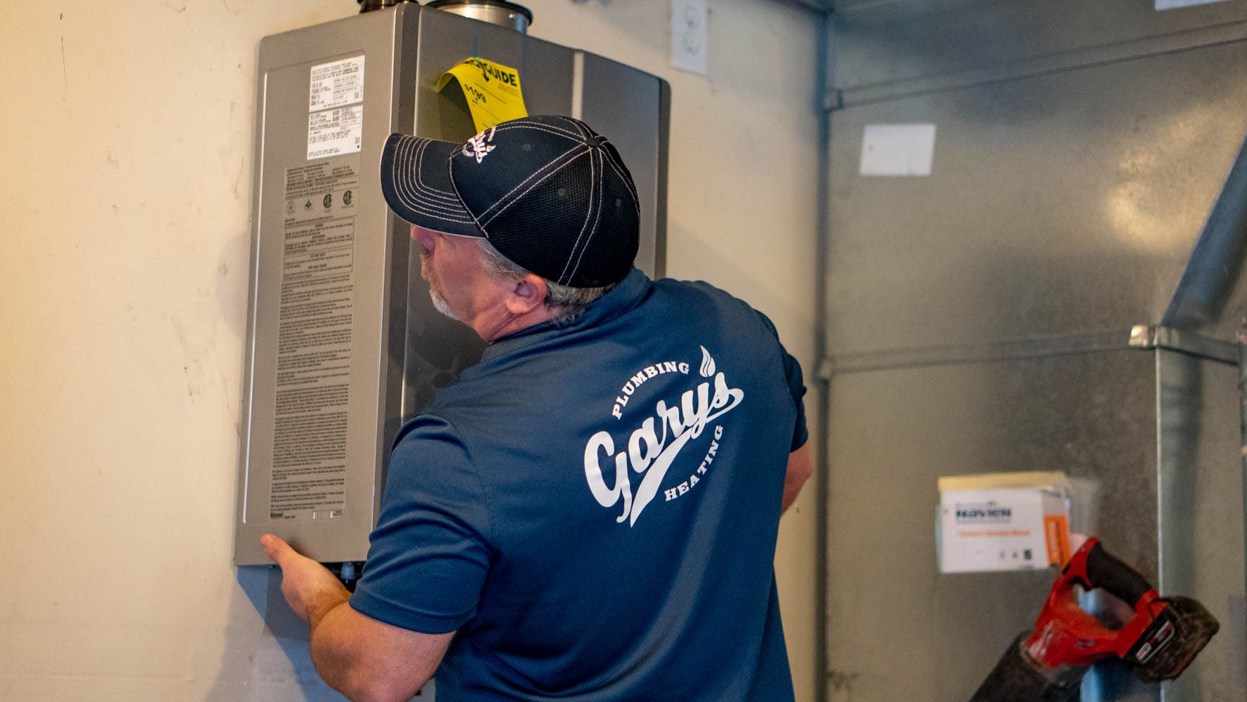 Technician in blue shirt inspecting an electrical panel in a utility room