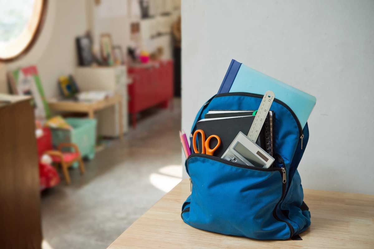 Blue backpack with school supplies on a table in a room