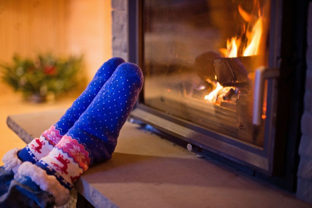 Feet in blue patterned socks warming by a fireplace with flames visible