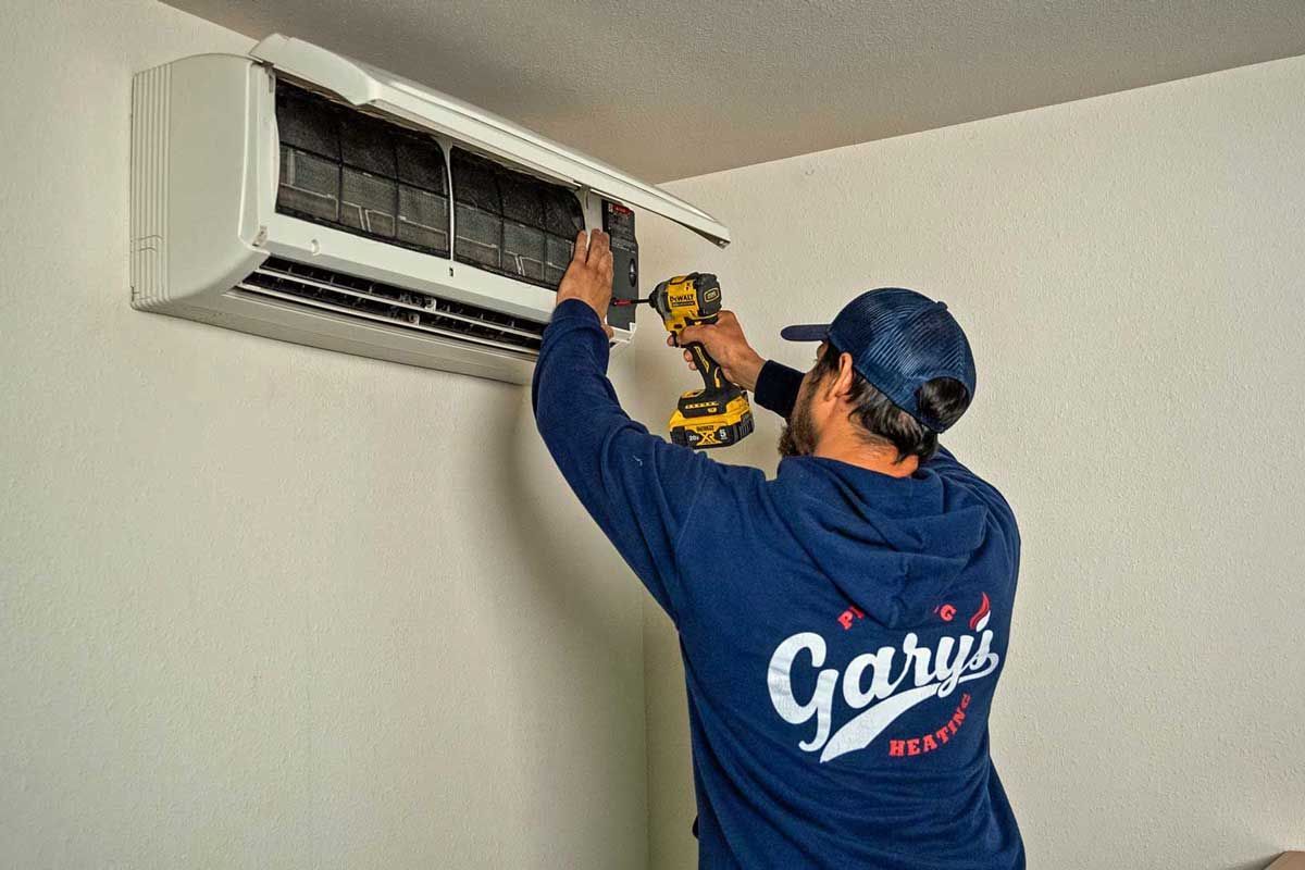 A Gary's technician is working on a mini-split system with a drill.