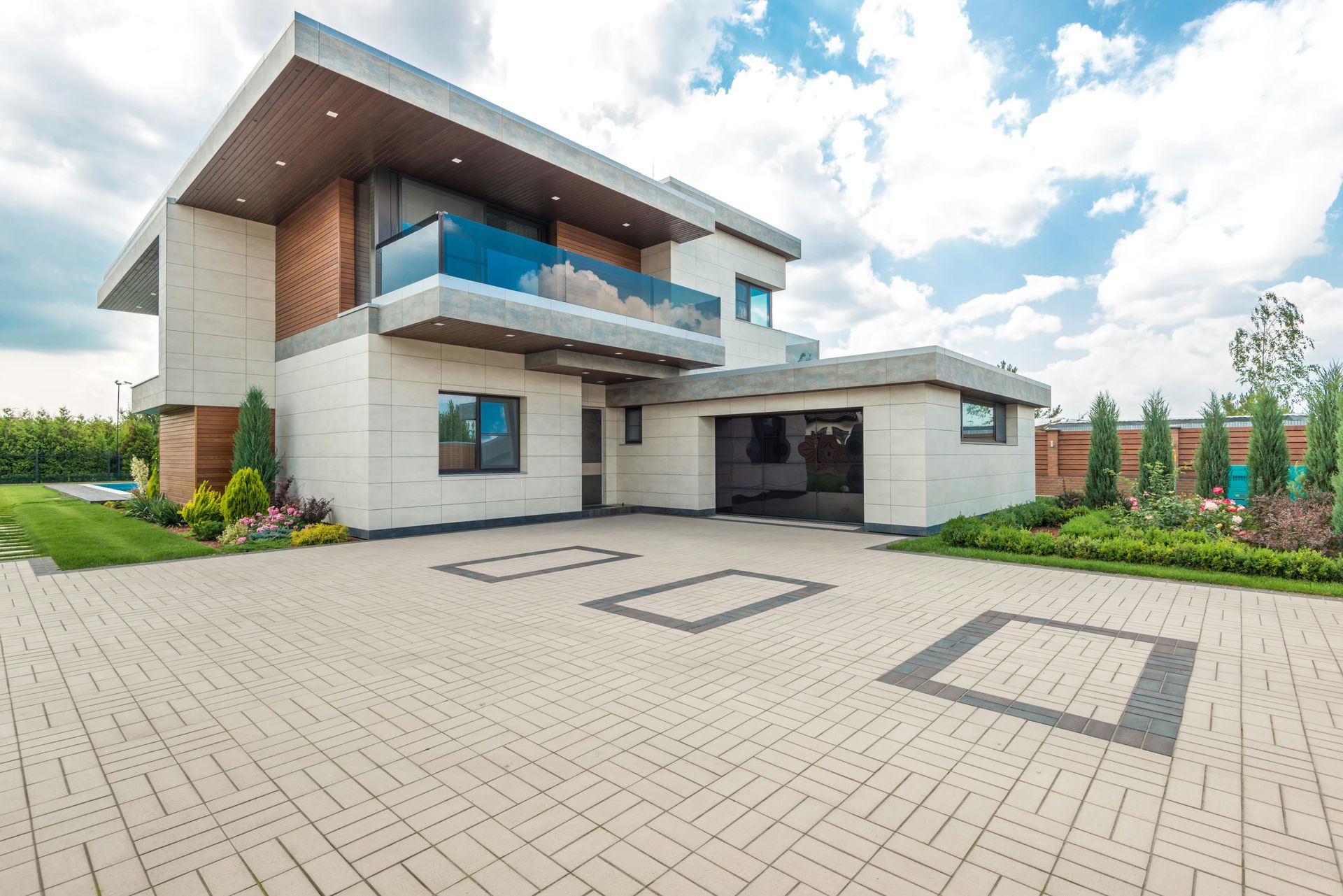 Modern two-story house with a paved driveway and open garage, blue sky in background.