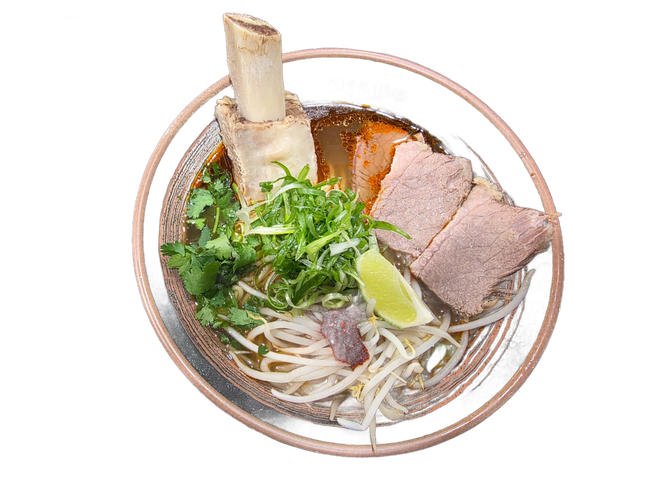 A bowl of ramen with chicken slices, marinated egg halves, bamboo shoots, and green onions in broth on a dark surface.