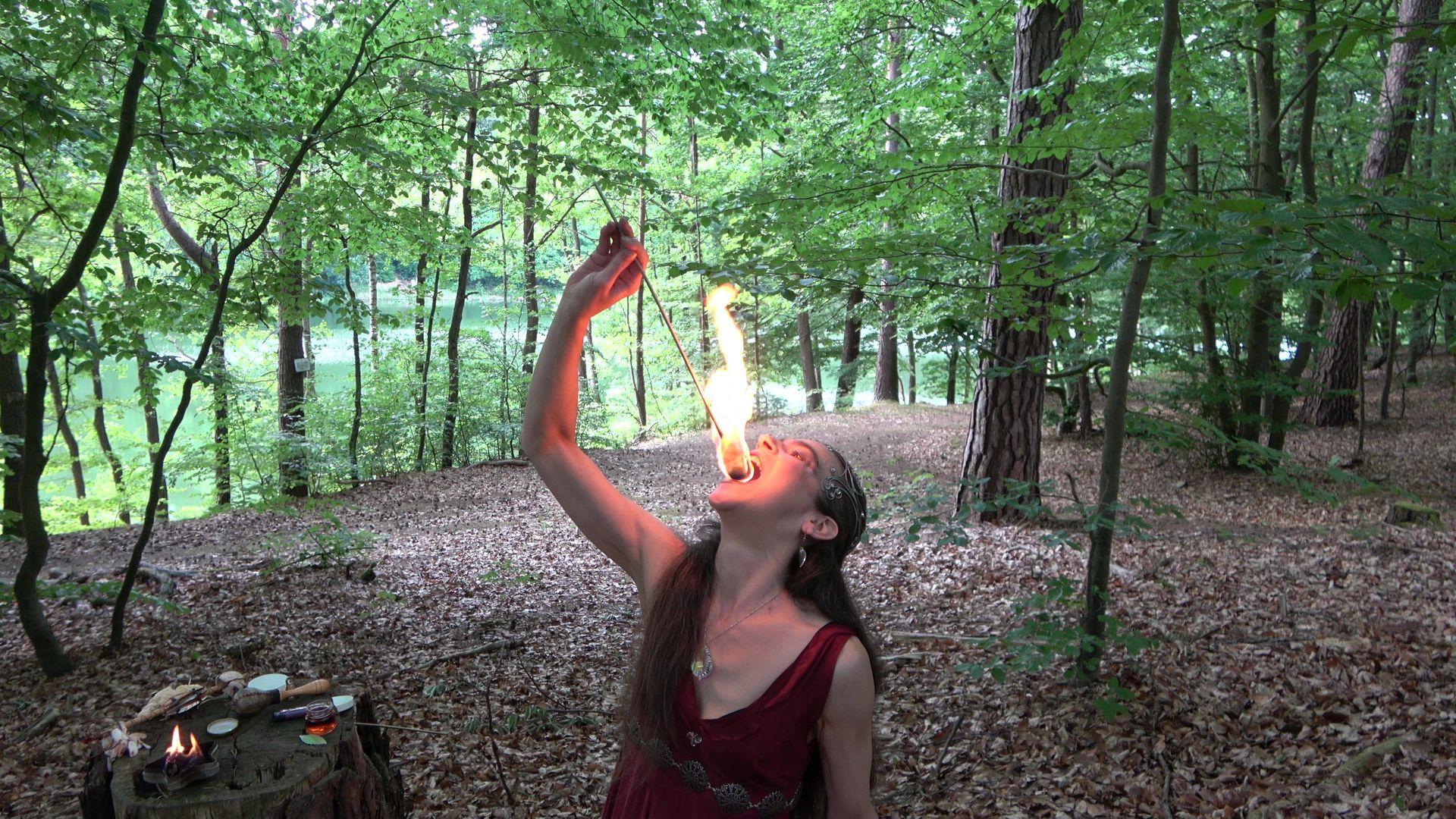 Eine Frau im roten Kleid schluckt im Wald Feuer