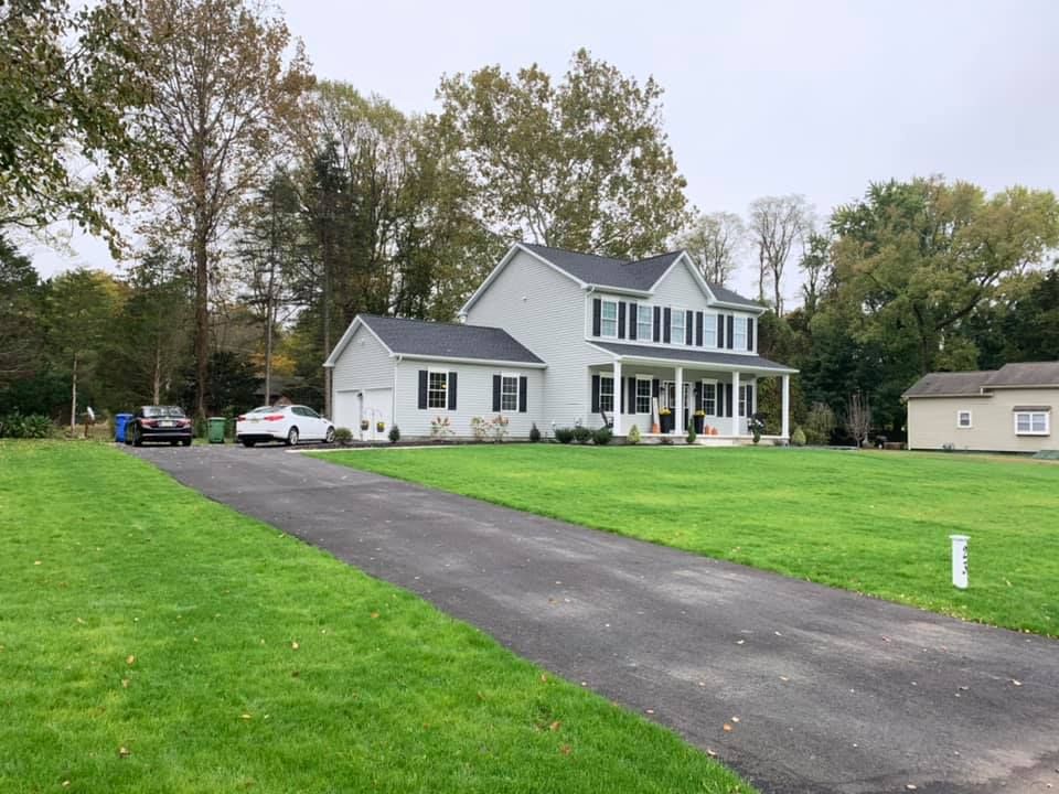 A large white house is sitting on top of a lush green field.