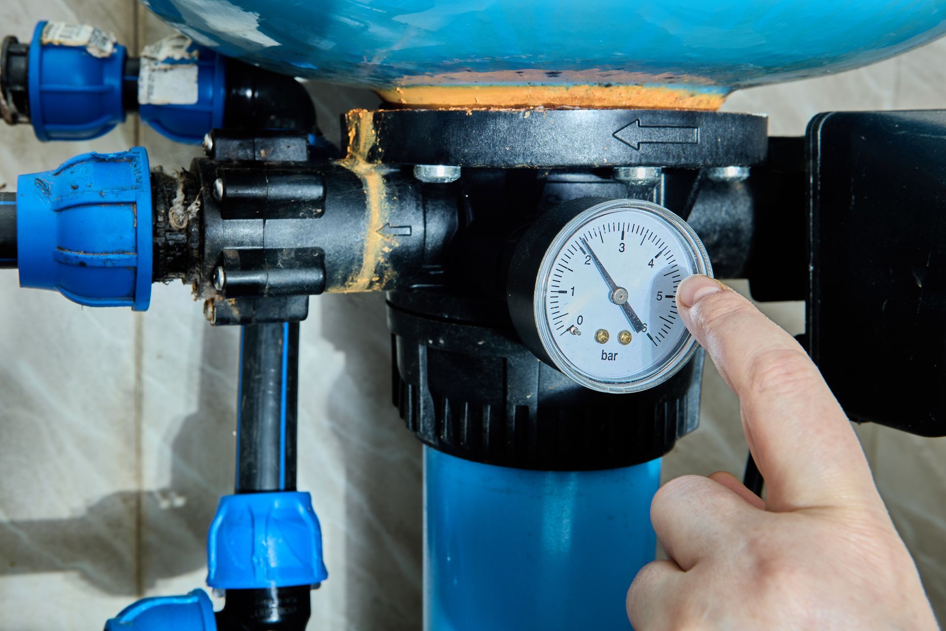 Person in blue shirt holding HVAC gauges with red, yellow, and black hoses.