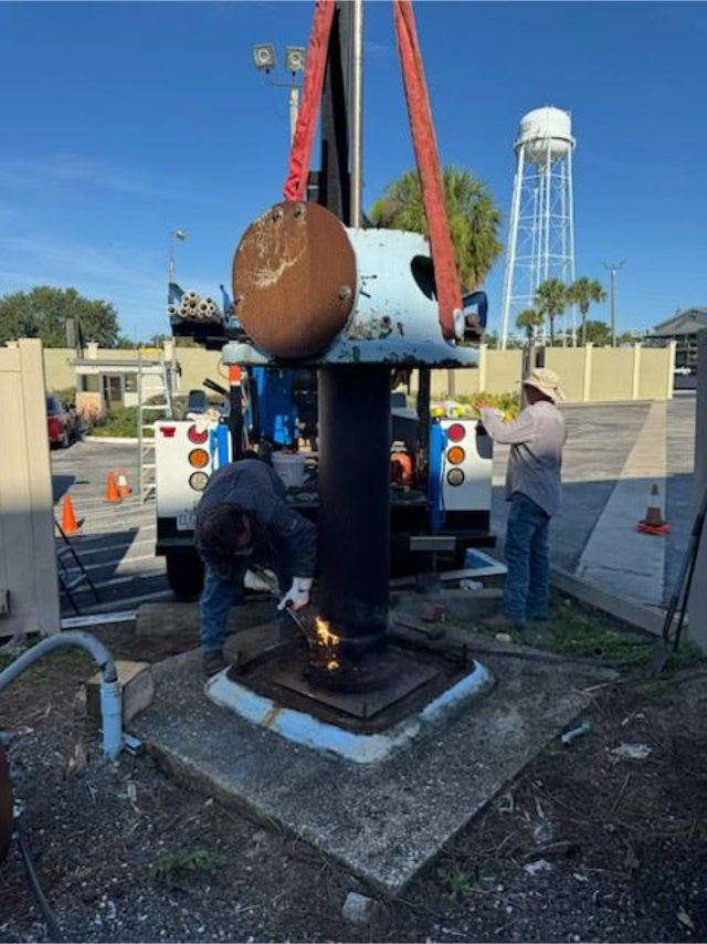 Person in blue shirt holding HVAC gauges with red, yellow, and black hoses.