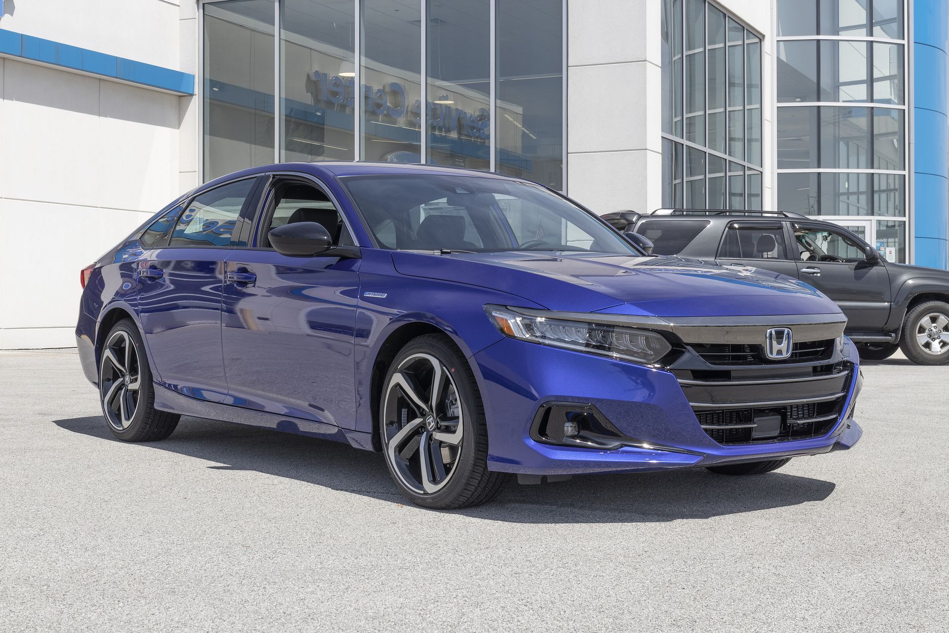 A blue Honda Accord sedan parked in front of a glass-fronted dealership building.