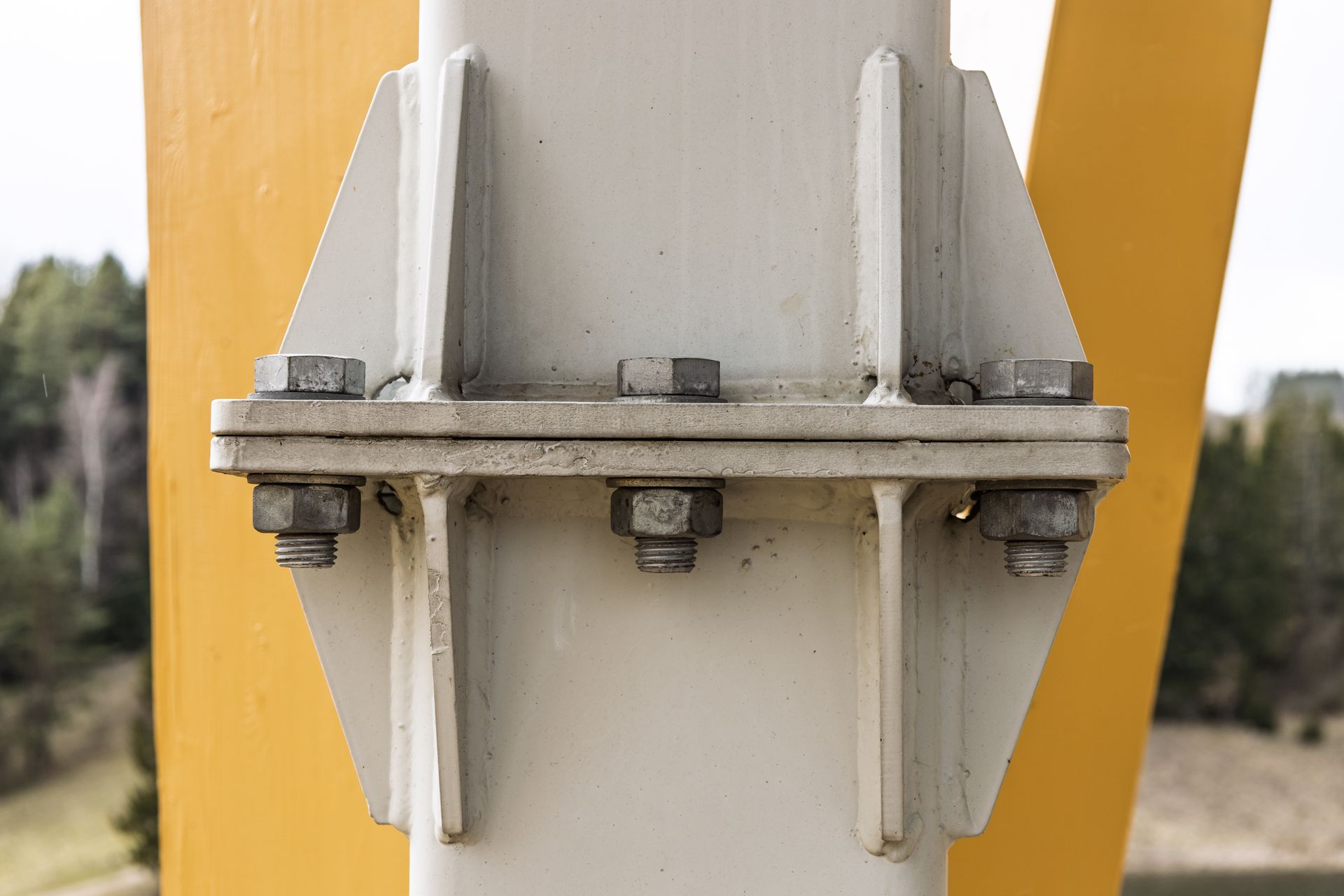 Close-up of a metal bolted joint on a white structure with yellow supports