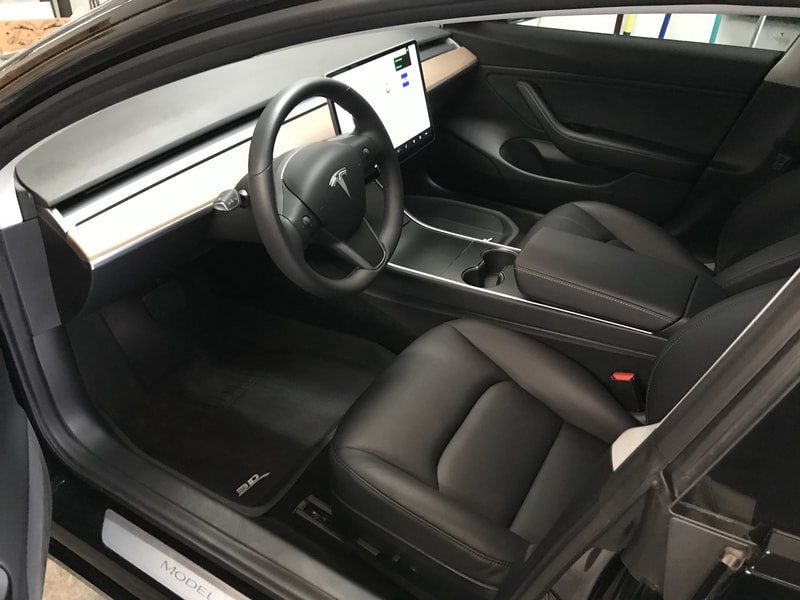 Tesla car interior with black seats, steering wheel, and center touchscreen