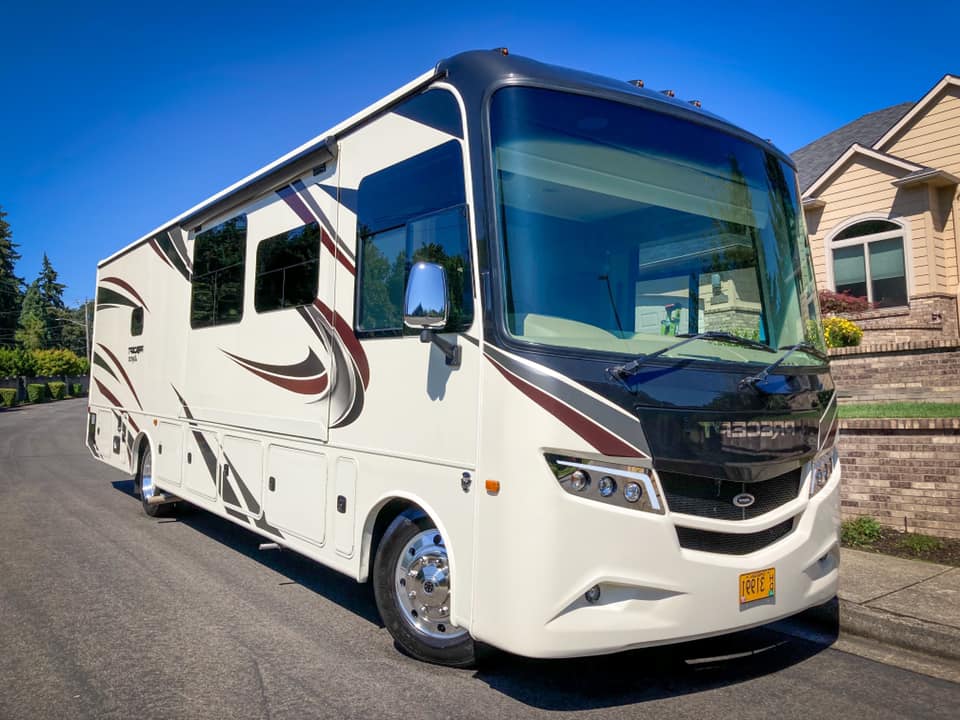 White luxury motorhome parked on a suburban street under a blue sky