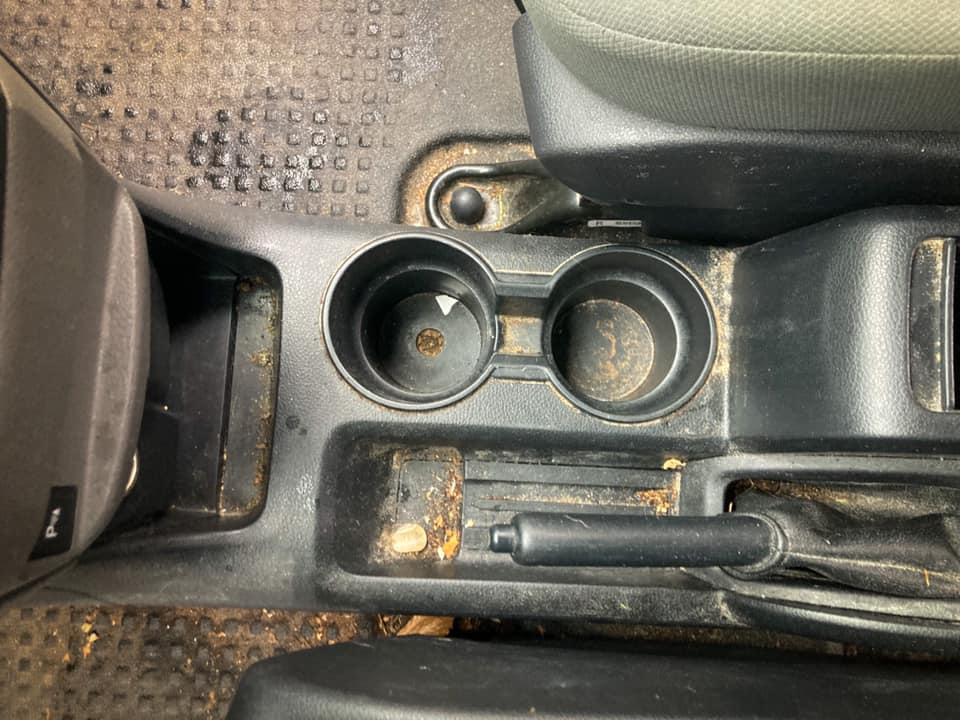Car cup holders and gear shift console with a worn black interior trim