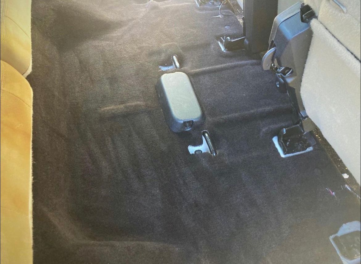 Car interior with black seats and a small light-colored center console or armrest on the floor.