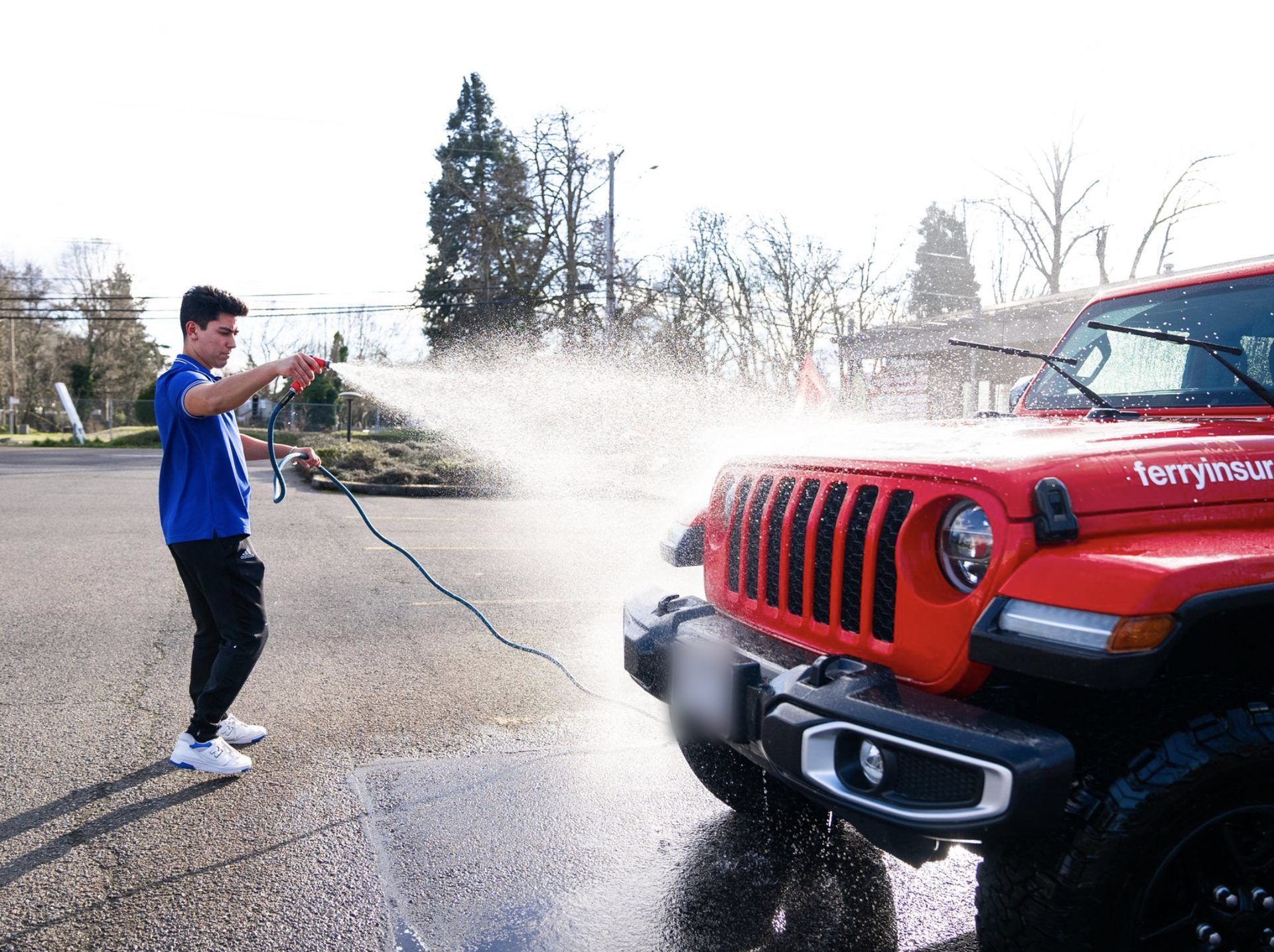 KeptCar detailer pressure washing a red Jeep Wrangler