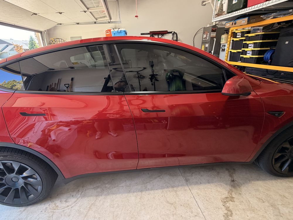 Red Tesla Model Y after front window tint by KeptCar, front windows now match the dark rear glass