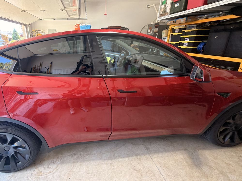 Red Tesla Model Y before window tint, with clear front windows and factory-dark rear windows