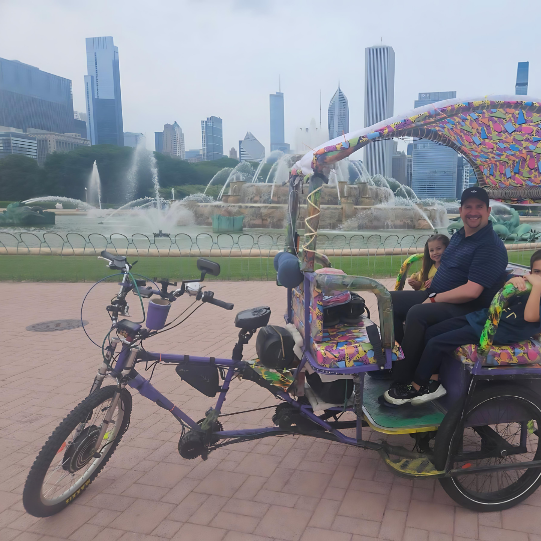 A family enjoys a scenic stop at Buckingham Fountain on their chicago rikshaw ride, a highlight of our family-friendly chicago sightseeing tours.
