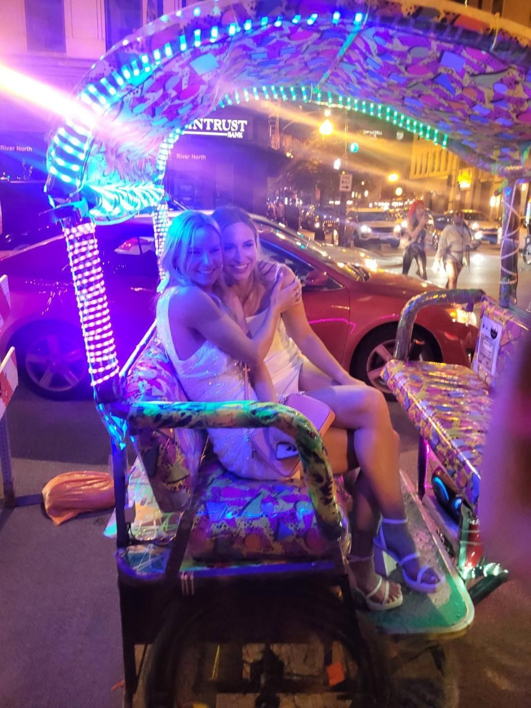 Two friends capture a memorable moment in a brightly lit pedicab during their chicago rikshaw ride, a highlight of our chicago pedicab tours.
