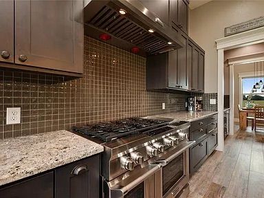 A modern kitchen with stainless steel appliances, dark cabinets, and a tiled backsplash.