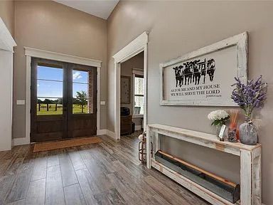 Entryway with wooden door, gray walls, wooden console table, and framed artwork.