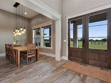 Dining room with wooden table and chairs, large double doors, and a light fixture.