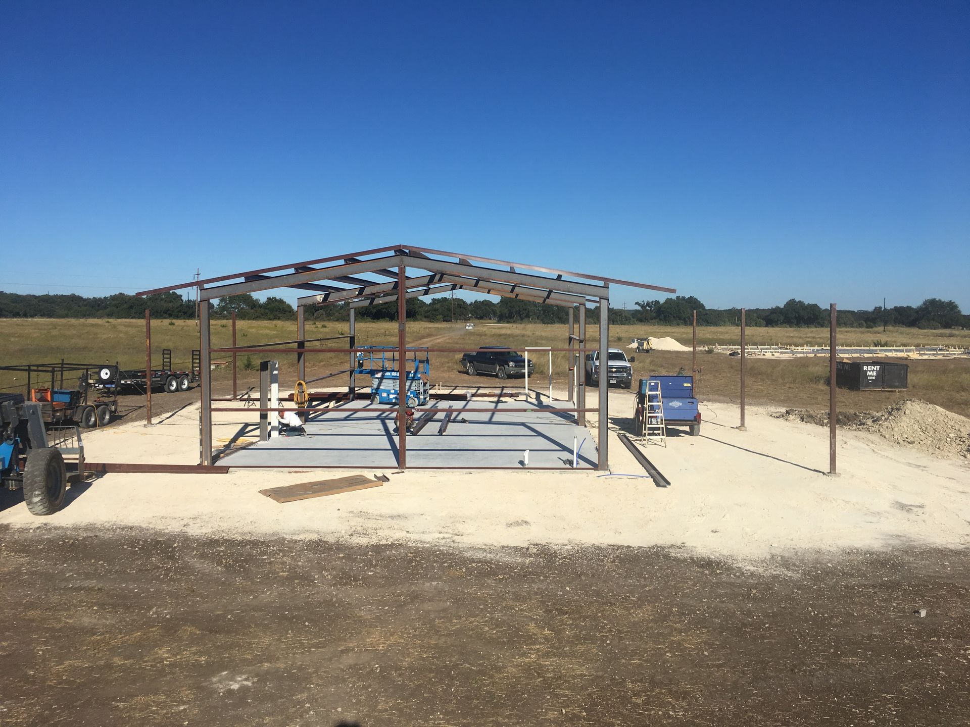 A metal framed structure under construction in a field on a sunny day.