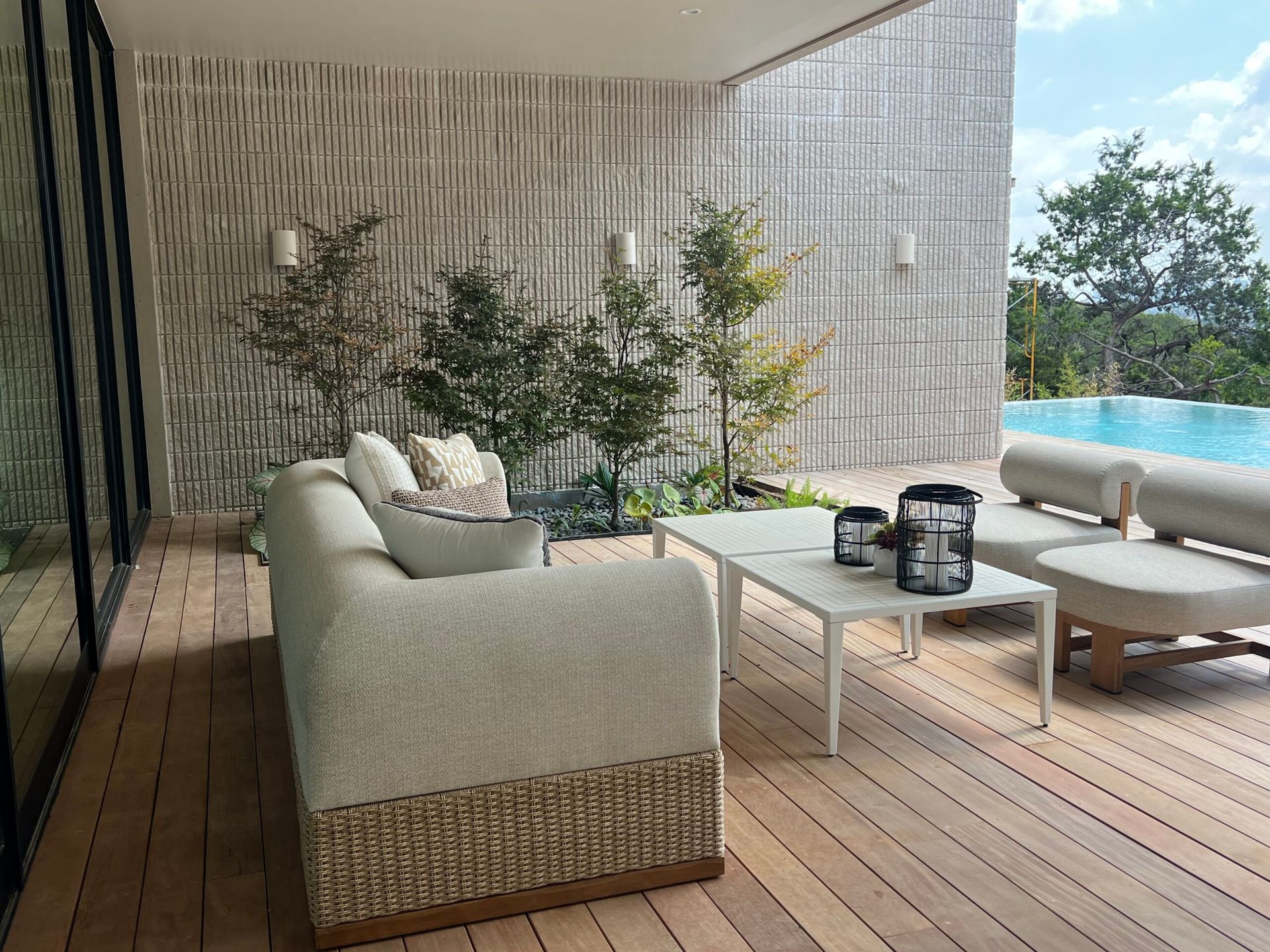 Patio with light sofa, white table, pool, and textured wall.