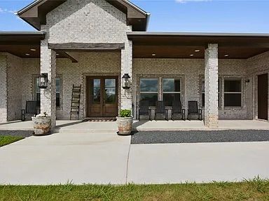 Brick home with a covered porch, wooden door, and a large concrete patio.