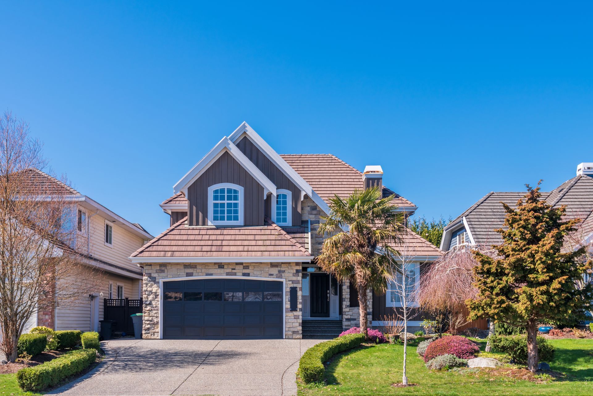 Two-story home with stone base dark wood siding tile roof and palm tree with location label reading Carmichael.